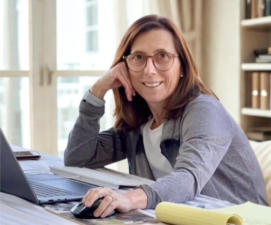 Web designer for small business working at home office — smiling at desk with laptop.