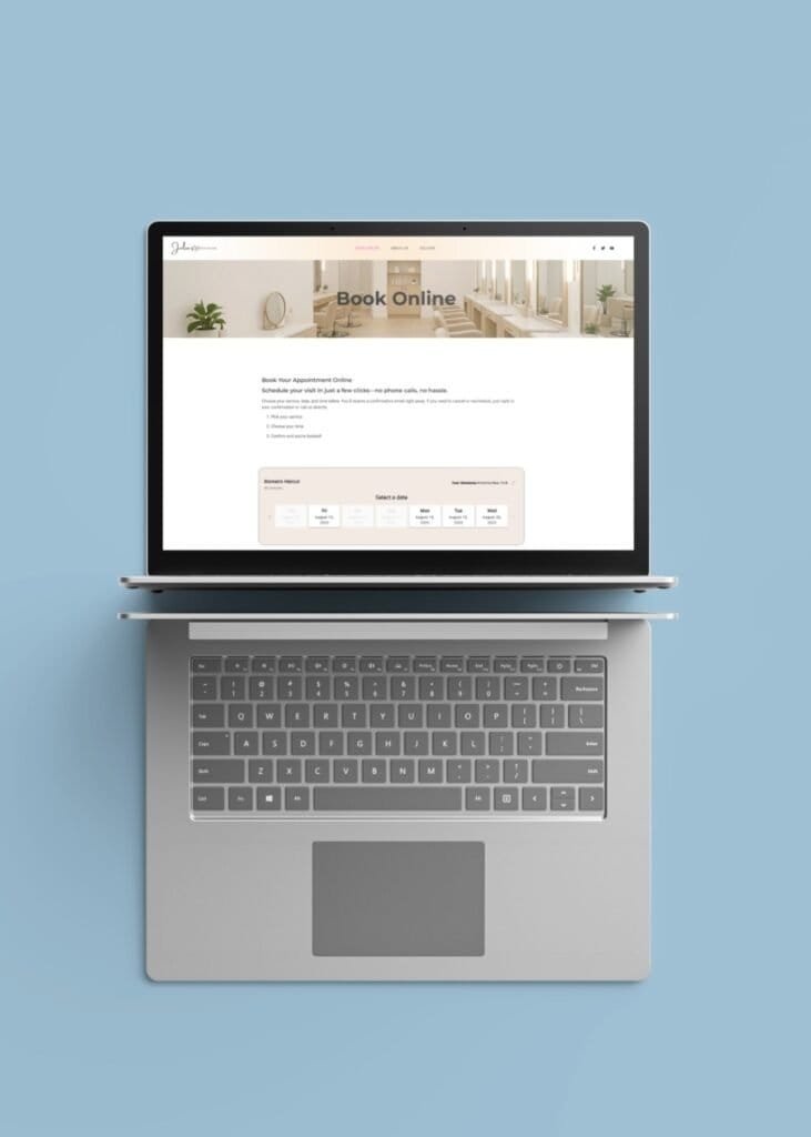 Overhead view of a silver laptop on a light blue background displaying Julie’s Hair Salon online booking page, featuring a clean interface with appointment scheduling options and a soft, neutral-toned salon image in the header.