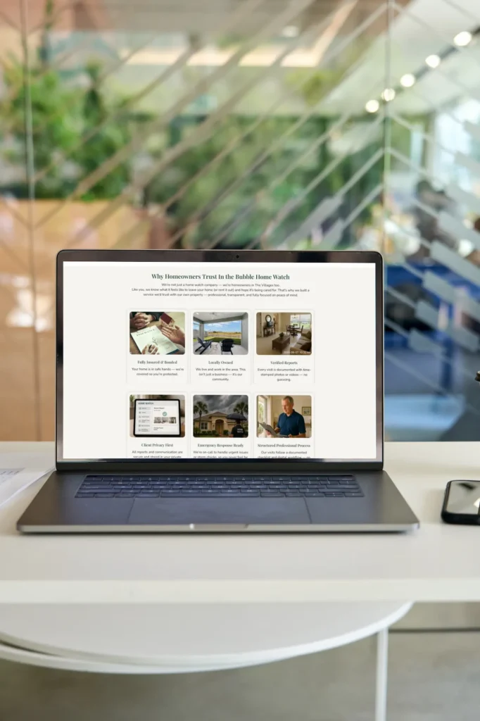 Office desk with a glass background. On the desk is a Laptop Showing In the Bubble Home Watch website.